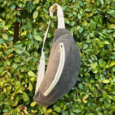 Mochila de veludo cotelê castanha pendurada em arbusto verde