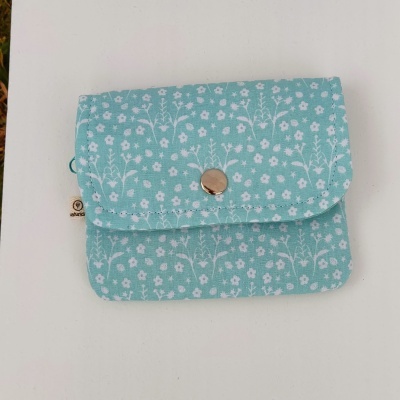 Bolsa pequena azul claro com padrão de flores brancas e botão prateado