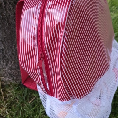 Mochila vermelha e branca com riscas e base de rede sobre relva
