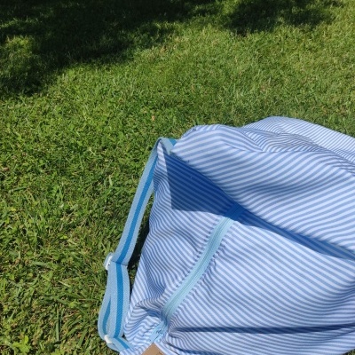 Mala azul e branca de riscas finas sobre relva verde