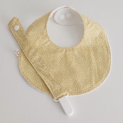 Babete bege com pequenos pontos brancos e fita para chupeta