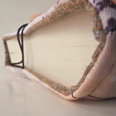 Livro com capa de tecido estampado e presilha de cabelo preta sobre superfície branca