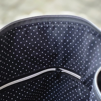Interior de mala com forro preto com padrão de pontos brancos e bolso com fecho branco