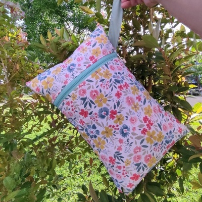 Mala pequena de tecido floral com fecho azul e pega cinzenta ao ar livre