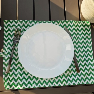 Mesa com prato branco e talheres sobre individual verde e branco