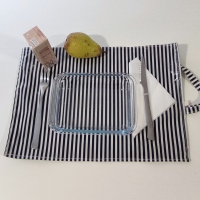 Jogo americano riscas pretas e brancas com talheres, prato de vidro, pera e embalagem de cartão