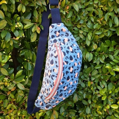 Bolsa pochete com padrão animal print pendurada em arbusto
