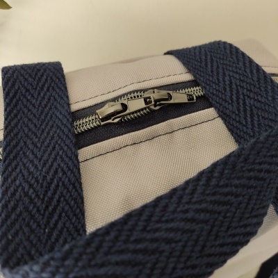 Mala bege com fecho de correr e alças azuis texturizadas