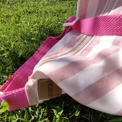 Mala ou saco às riscas rosa e branca com alça rosa na relva