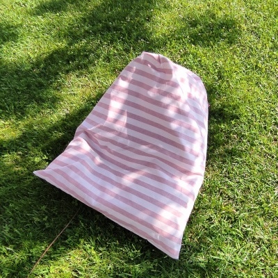 Saco têxtil riscas rosa e branco sobre relva verde