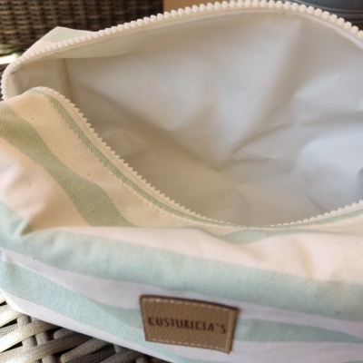 Necessaire riscada verde água e branco aberta com etiqueta CUSTURICIA'S