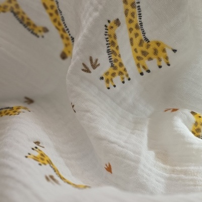 Tecido branco com padrão de girafas amarelas e manchas castanhas