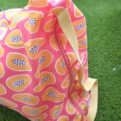 Mochila colorida com padrão de frutos sobre relva artificial