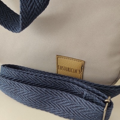 Mala bege com alça azul escuro e etiqueta de couro