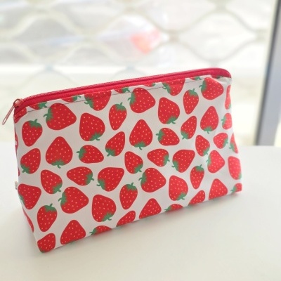 Necessaire branca com padrão de morangos vermelhos e fecho vermelho