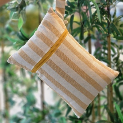 Bolsa quadrada às riscas amarelas e brancas com fecho amarelo e alça, em fundo de plantas