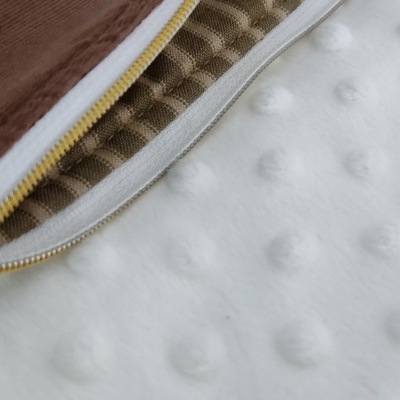 Bolsa castanha com fecho dourado e interior almofadado sobre superfície branca texturizada