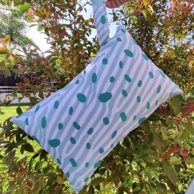 Bolsa pequena de tecido branco com padrão verde e rosa em ambiente exterior