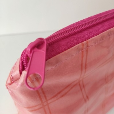 Estojo rosa claro com padrão xadrez e fecho correr rosa