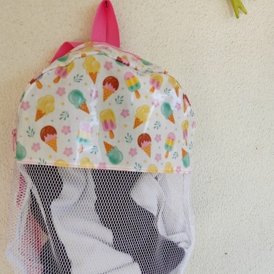 Mochila colorida com padrão de gelados pendurada numa parede com gancho de pássaro verde