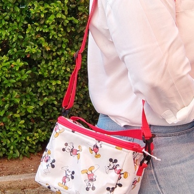 Mala tiracolo branca com desenhos animados coloridos e fecho vermelho