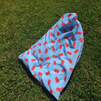 Tecido azul claro com padrão de gelados vermelhos sobre relva verde