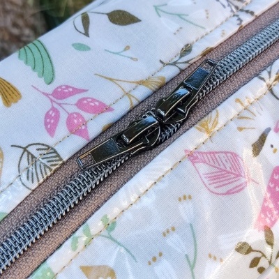 Mochila branca com padrão floral e fecho metálico duplo