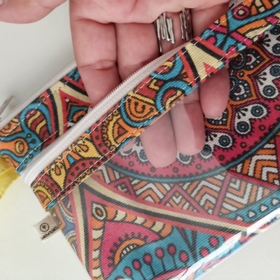 Bolsa pequena com padrão étnico colorido e fecho de correr