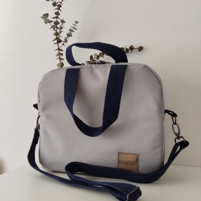 Bolsa retangular cinza com alças azul escuro e etiqueta COSTUMICA Y