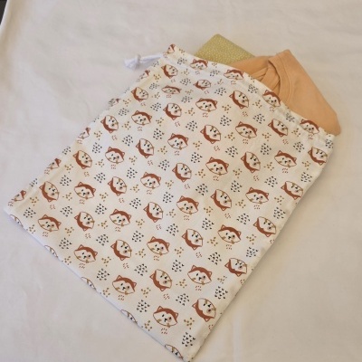 Saco de tecido com padrão raposa, peça de roupa pêssego e tecido verde sobre fundo branco