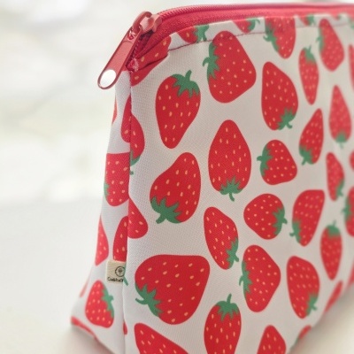 Estojo branco com padrão de morangos vermelhos e fecho vermelho