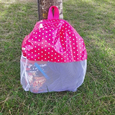 Mochila rosa com estrelas brancas e rede branca em relva junto a árvore