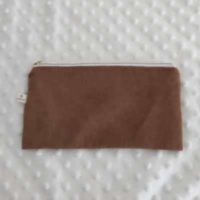 Estojo castanho claro com fecho dourado sobre fundo branco texturizado