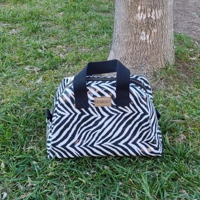 Bolsa pequena padrão zebrado preto e branco no relvado junto a uma árvore