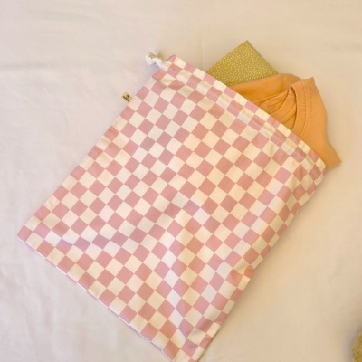 Saco rosa claro e branco de quadrados com t-shirt laranja e caderno amarelo com pontos brancos