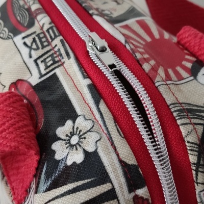 Mala de tecido com padrão gráfico vermelho e bege e fecho de correr branco