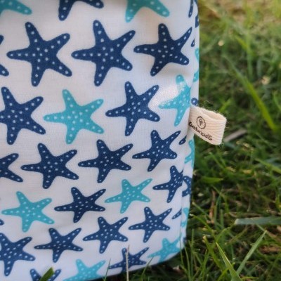 Necessaire azul com padrão de estrelas-do-mar sobre relva