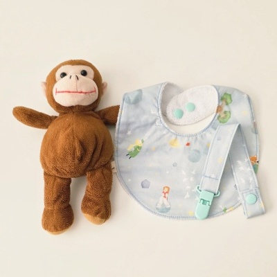 Boneco de peluche macaco castanho, babete azul claro com padrão e fita para chupeta azul