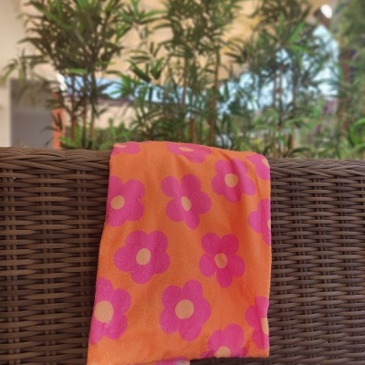 Manta cor-de-rosa com flores cor-de-rosa pendurada em sofá de vime