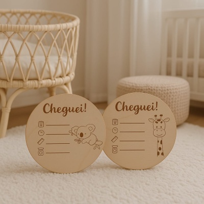 Discos de madeira para anúncio de bebé com texto Cheguei! e ilustrações de coala e girafa, sobre tapete claro em quarto infantil