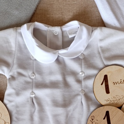 Body branco para bebé com gola redonda e botões, discos de madeira com texto em português ao lado