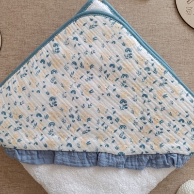 Toalha de bebé com capuz estampado com coelhinhos e detalhes azuis.