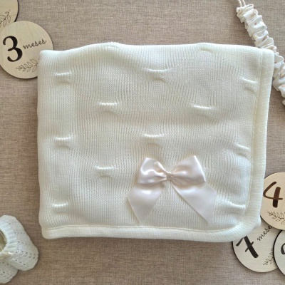 Manta de bebé branca em malha com laço de cetim, placas de madeira com números, sapato de croché branco