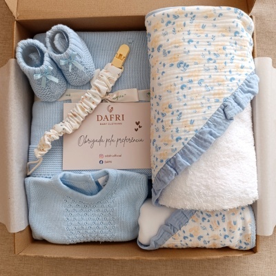 Caixa com roupa e manta de bebé azul, sapatinhos tricotados e cartão de agradecimento