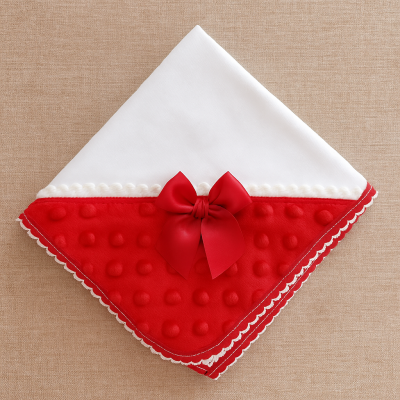 Pano de bebé com parte branca lisa e parte vermelha texturizada com bolinhas e laço vermelho.