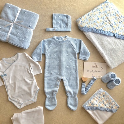 Vestuário para bebé azul e branco com acessórios numa superfície neutra.