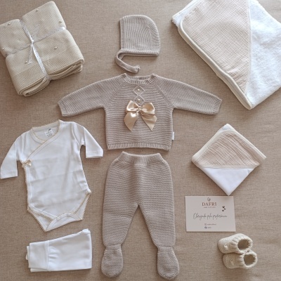 Conjunto de roupa para bebé com body branco, peças de malha cinzenta e acessórios têxteis.
