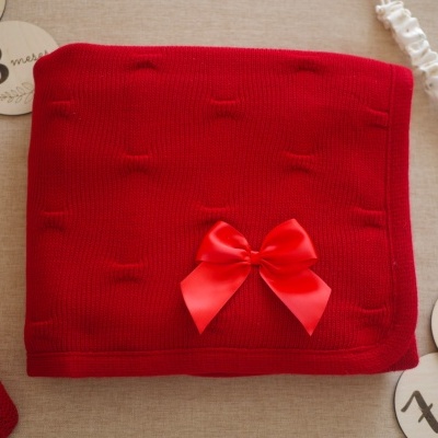 Cobertor vermelho tricotado com laço vermelho e discos com números para meses