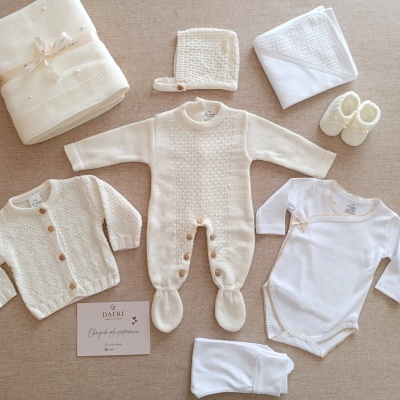 Conjunto de roupa de bebé branco e bege com vários itens de malha e algodão