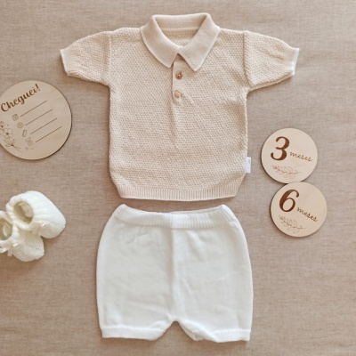 Conjunto de roupa de bebé em malha bege claro e branco com placas de madeira redondas